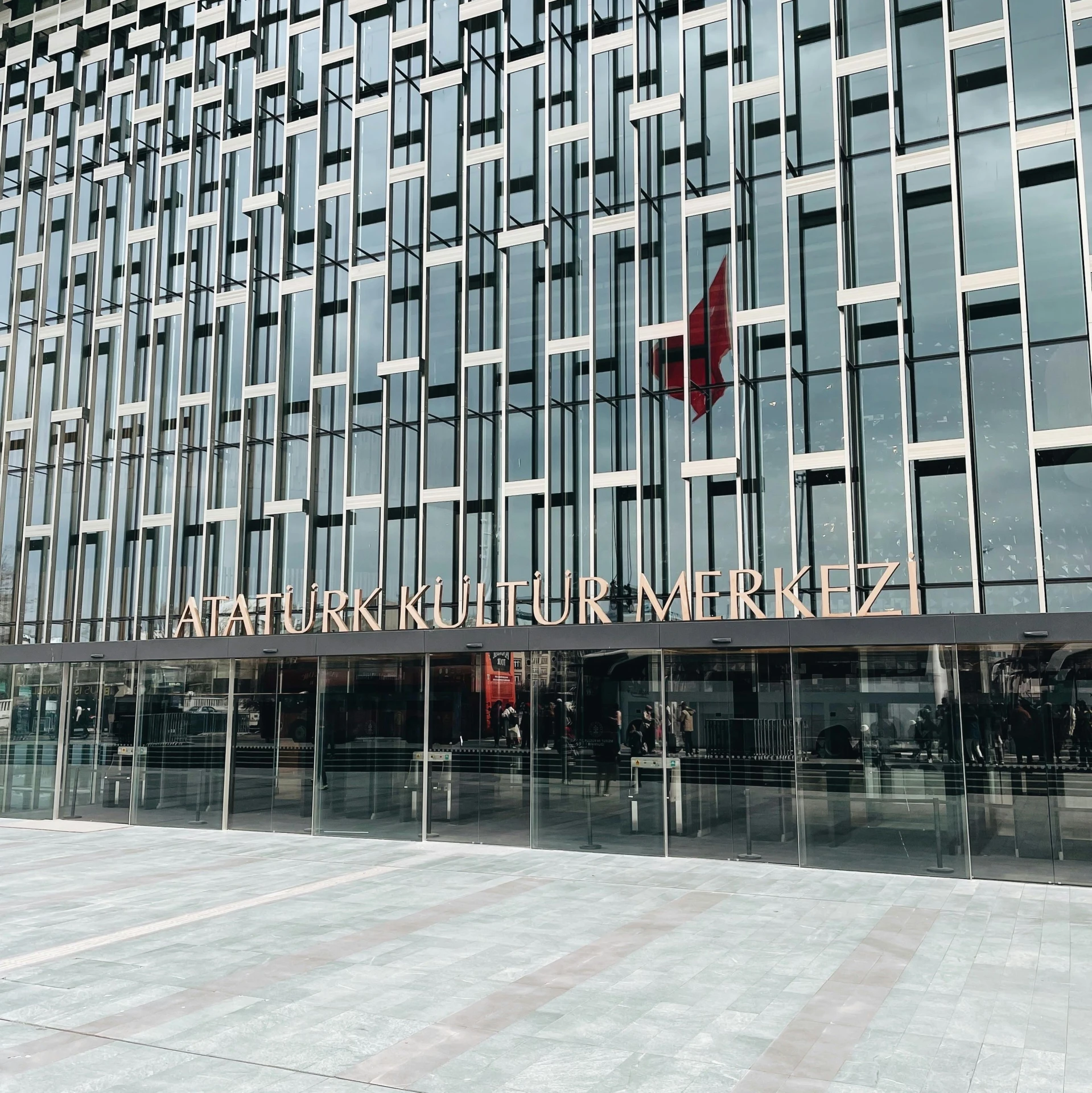 a large glass building with a red flag in front of it, hurufiyya, arper's bazaar, photo on iphone, high-quality photo, front face