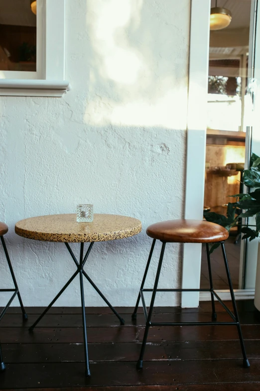 two stools next to a table and potted plant