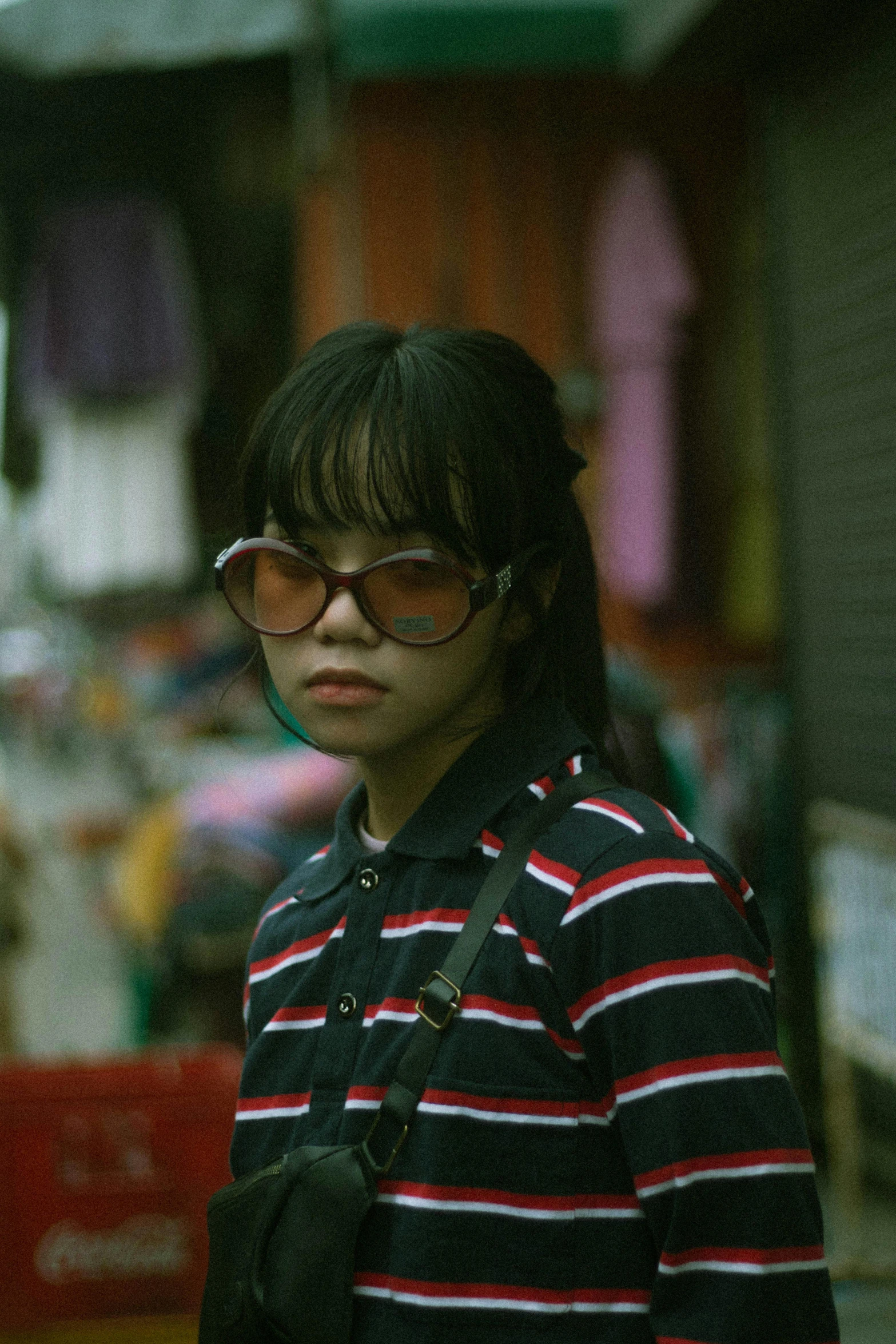 a woman wearing glasses and a striped shirt, an album cover, inspired by Liam Wong, pexels contest winner, realism, street wear, south east asian with round face, vintage color, young girl