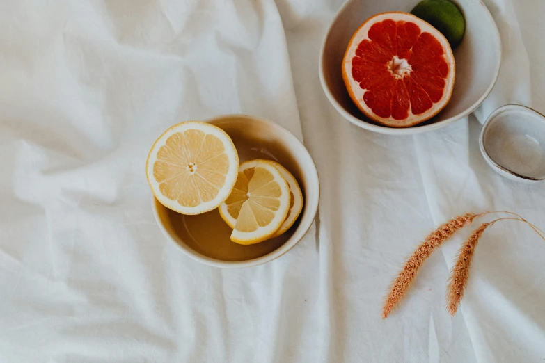 a bowl of fruit sitting on top of a bed, trending on pexels, drinking tea, with lemon skin texture, white and orange, background image