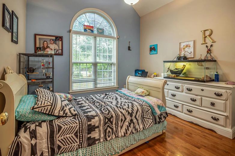 a bed sitting under a large arched window in a bedroom