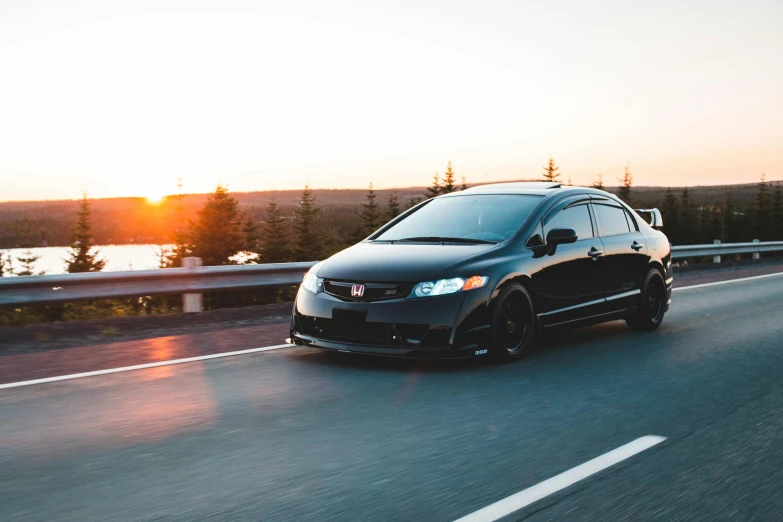 a black car driving down a road next to a body of water, by Matt Cavotta, pexels contest winner, honda civic, sundown, 🚿🗝📝, long front end