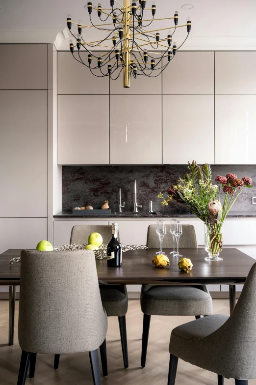 a dining table surrounded by grey chairs next to a sink