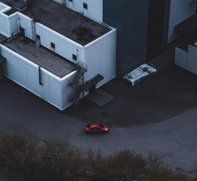 a red car is parked in front of a building, inspired by Elsa Bleda, pexels contest winner, aerial footage, car chase, industrial space, black car