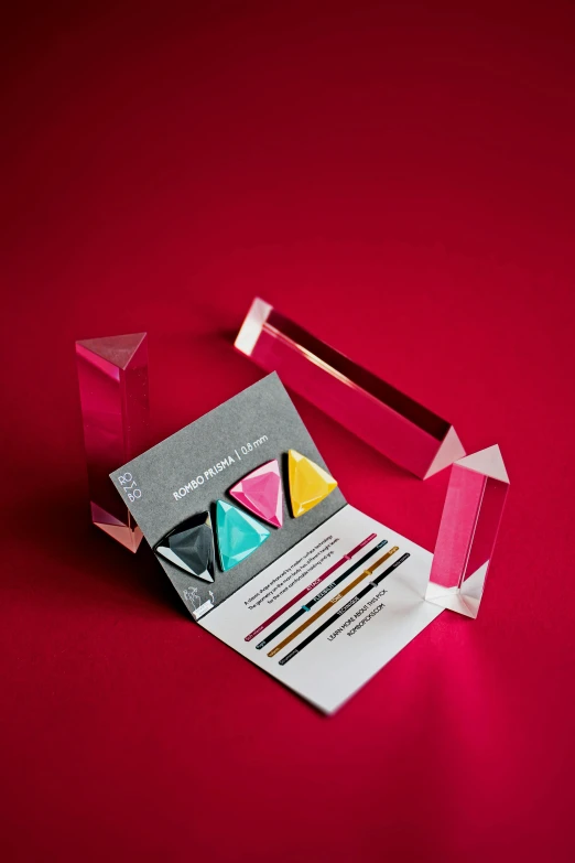 a credit card sitting on top of a piece of paper, an abstract sculpture, inspired by Frederick Hammersley, crystal cubism, hot pink and gold color scheme, packaging award, glass obelisks, vibrant powder paints