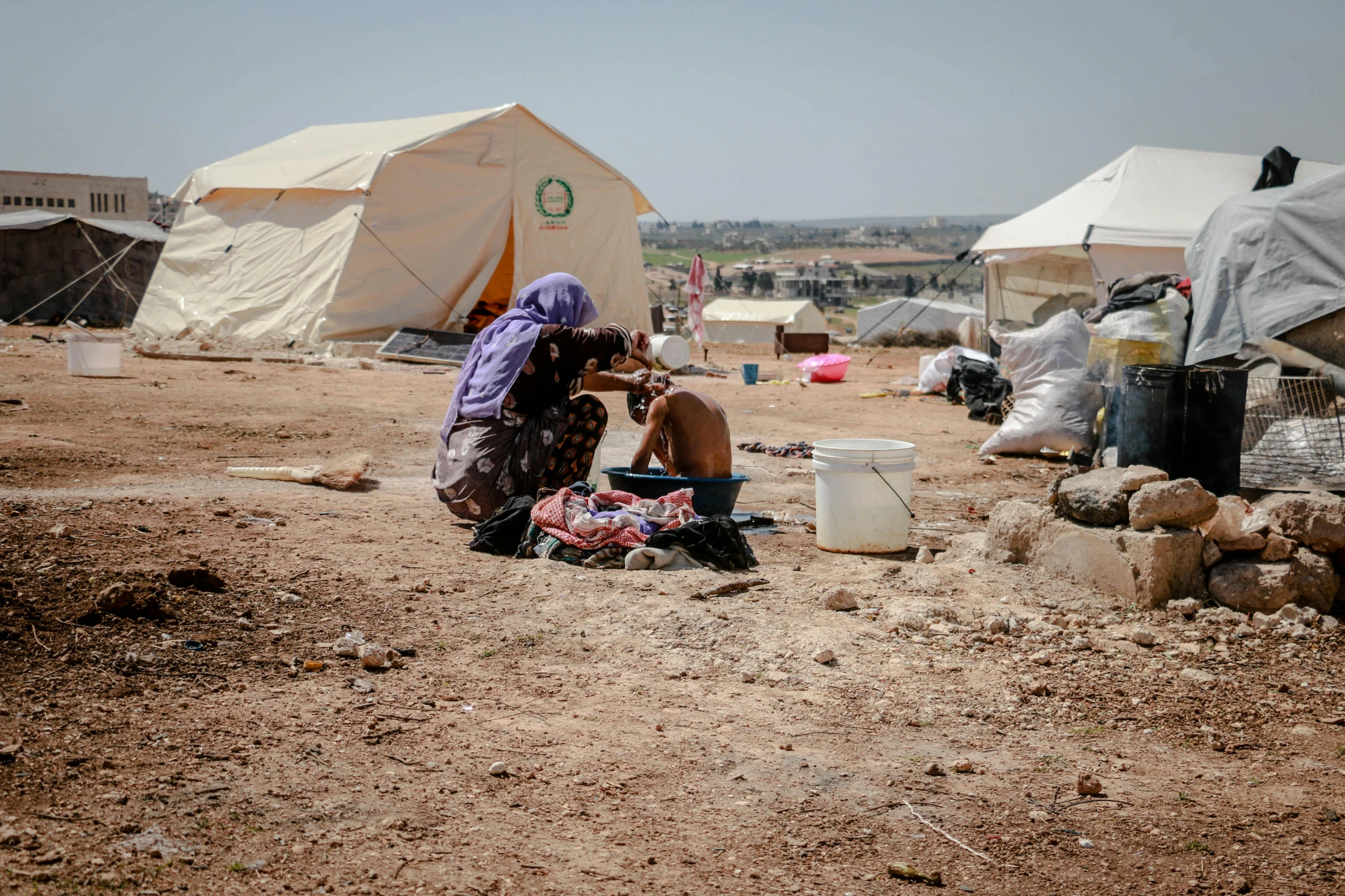 a woman sitting on the ground in front of a tent, hurufiyya, a friend in need, realistic »