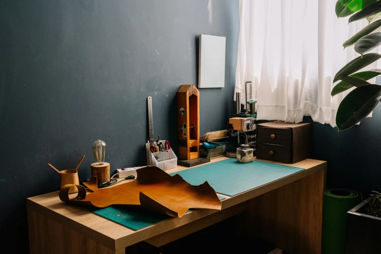 a desk with a lot of things on it, by Alejandro Obregón, trending on pexels, arts and crafts movement, leather apron, amber and blue color scheme, kyoto studio, minimalistic art