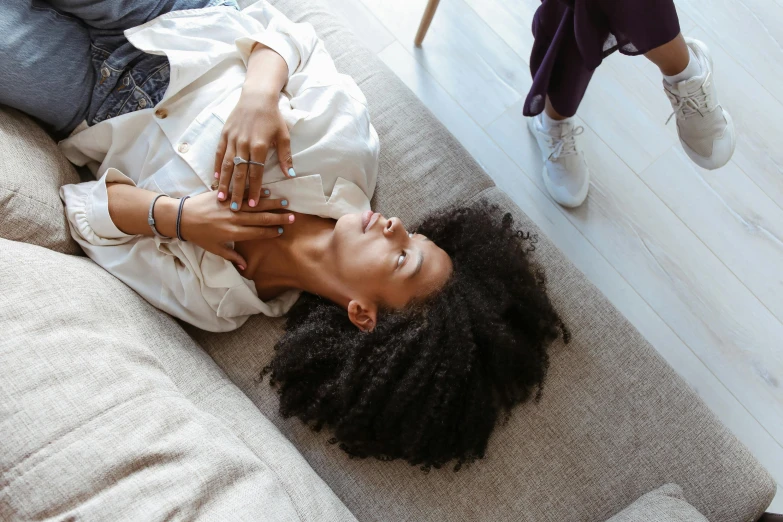 a woman laying on top of a couch in a living room, trending on pexels, natural hair, touching heads, connection rituals, high angle shot