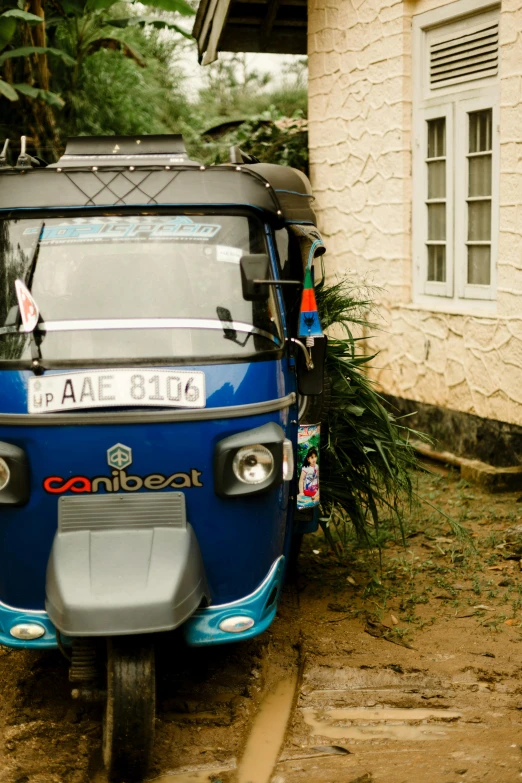 a small, blue and gray vehicle parked near a white building