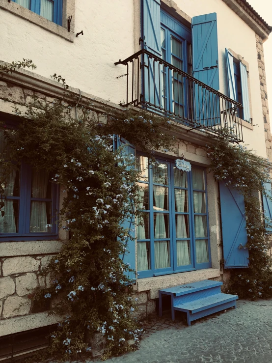 a blue bench is under a beautiful building with shutters and iron balconies