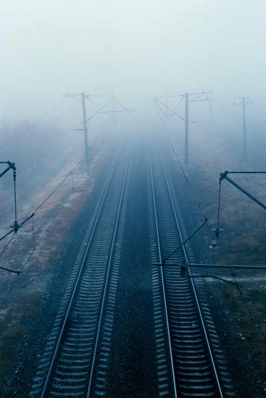 a train track in the foggy air with lots of trees