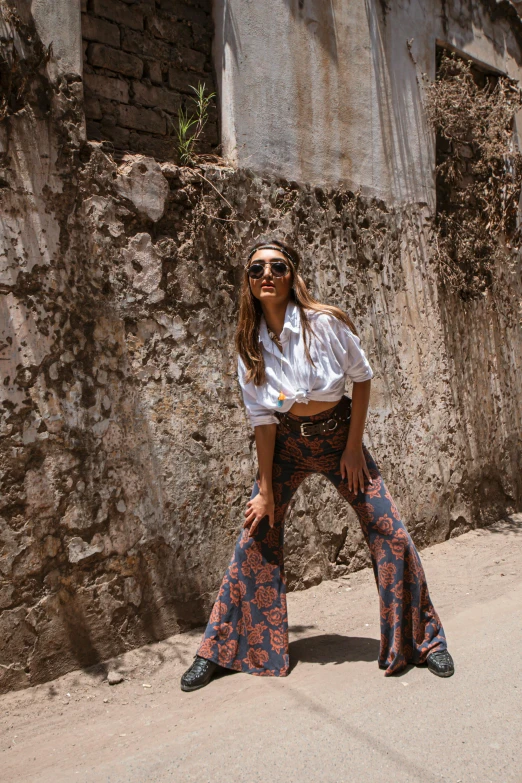 a woman standing on the side of a road, trending on pexels, clothed in ancient street wear, bali, flares, paisley