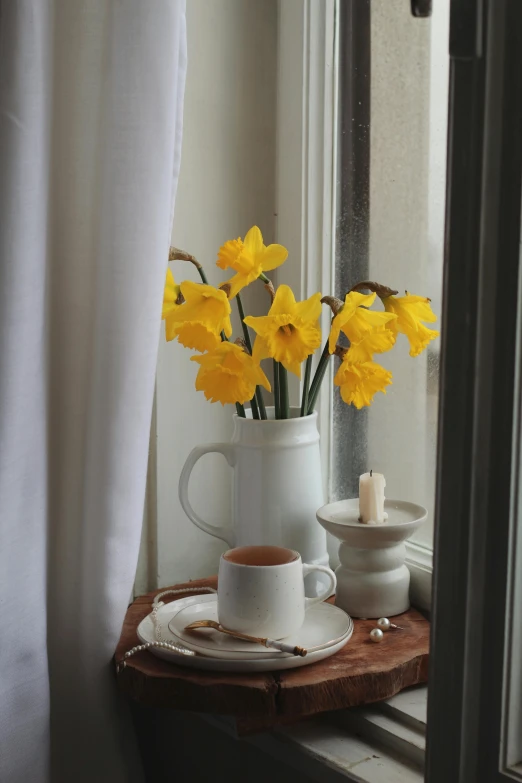 a tea cup with a drink next to some flowers in a window sill