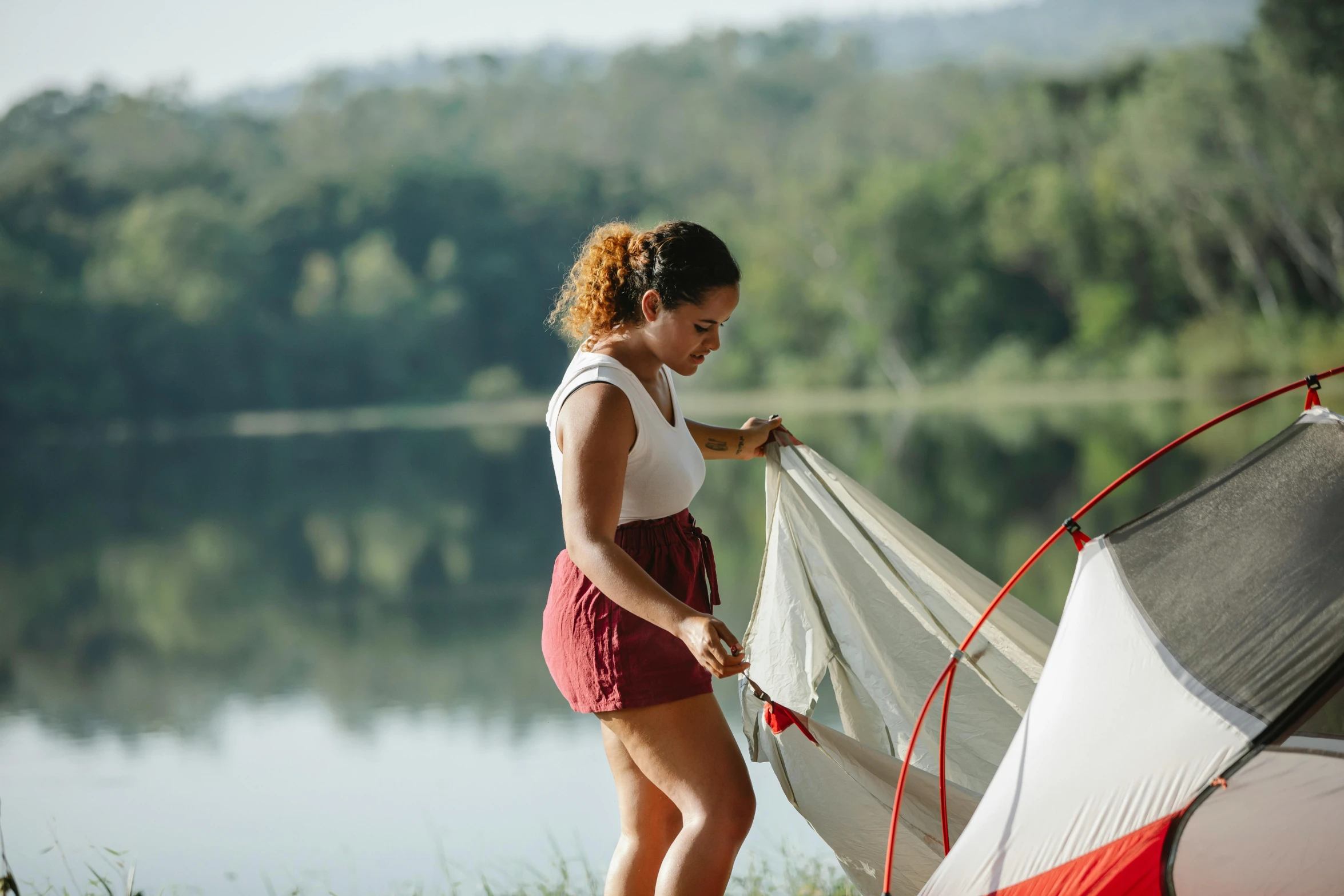 a woman standing next to a tent next to a lake, stretch, profile image, maintenance, lachlan bailey
