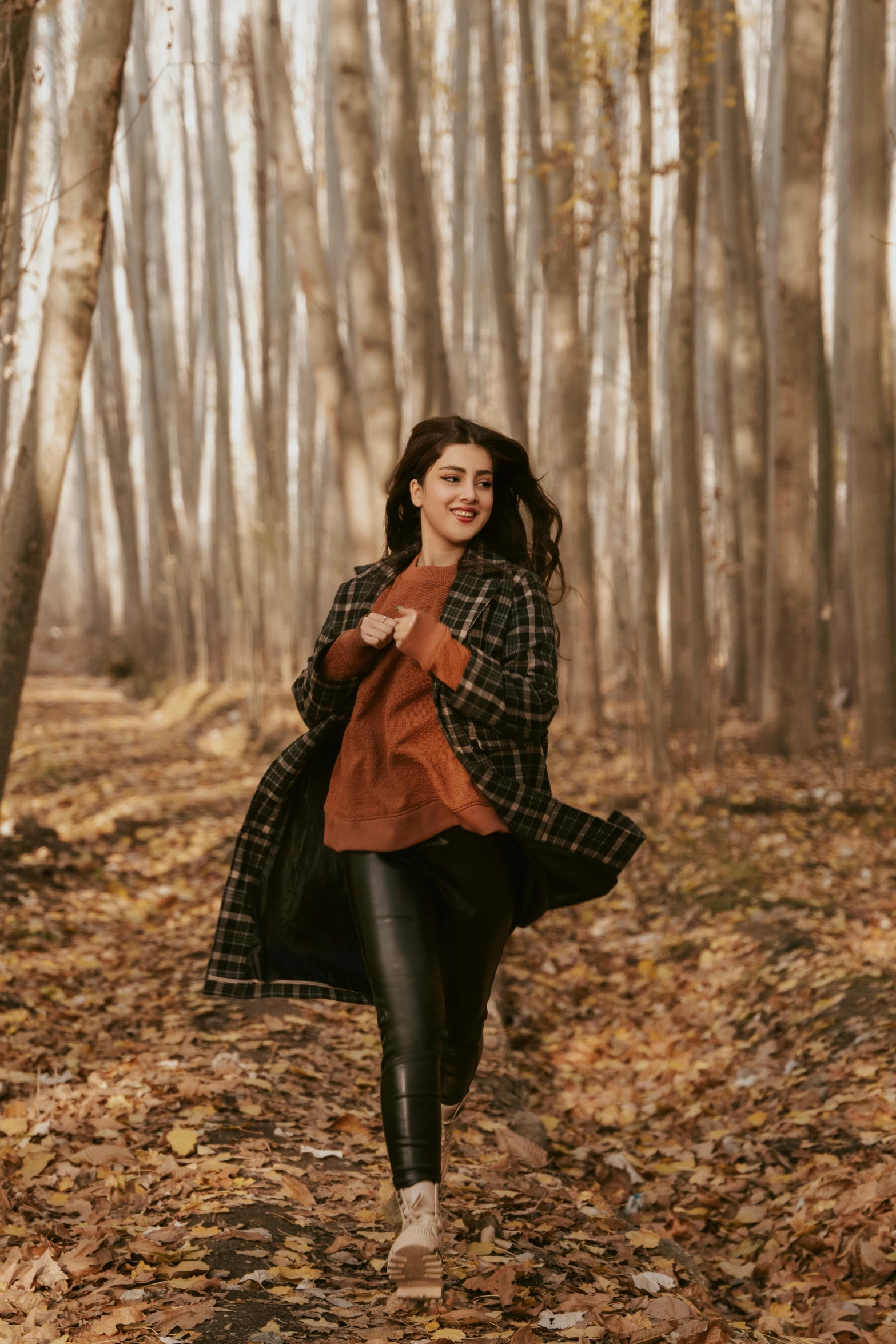 a woman walking through a forest in the fall, pexels contest winner, arabesque, mutahar laughing, leather clothing, plaid tights, young middle eastern woman