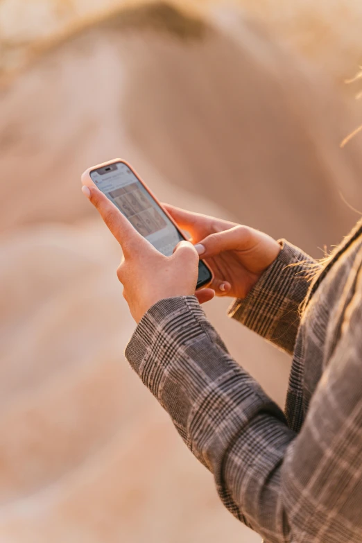 a close up of a person holding a cell phone, trending on pexels, in the desert, informative texts, warm hues, corporate phone app icon