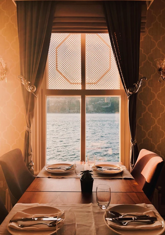 a dining room table with a wooden dining set near a window overlooking water