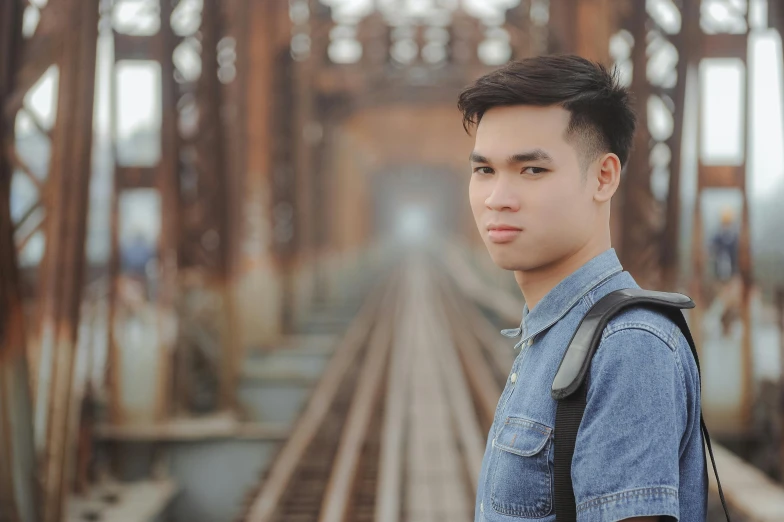 a boy standing near a train track on a bridge
