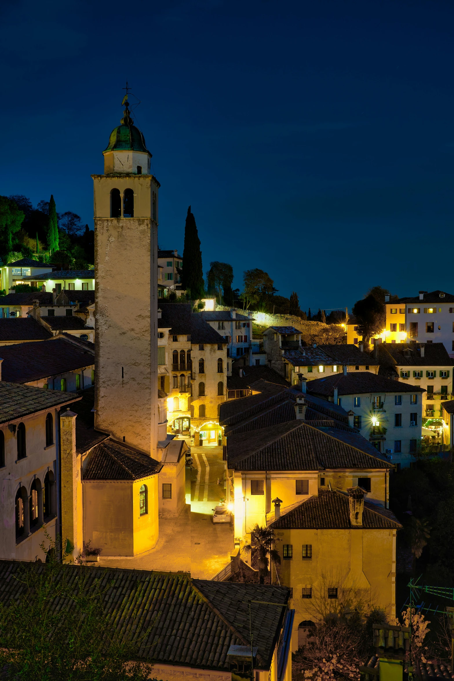 a view of a town at night with a clock tower, bizzaro, beautifully lit buildings, abbondio stazio, profile image