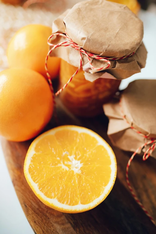 a wooden cutting board topped with oranges and jam, gifts, uncropped, paper, half image