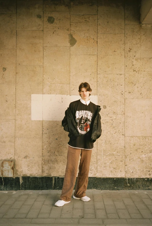 a man standing in front of a wall with a skateboard, an album cover, by Attila Meszlenyi, renaissance, wearing sweatshirt, portrait of 1 5 - year - old boy, androgynous person, 1996)