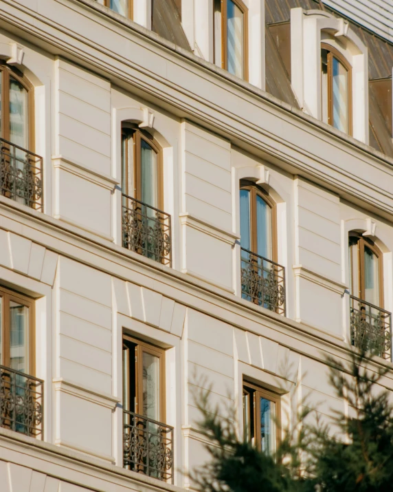 the building has several windows, balconies and a few trees