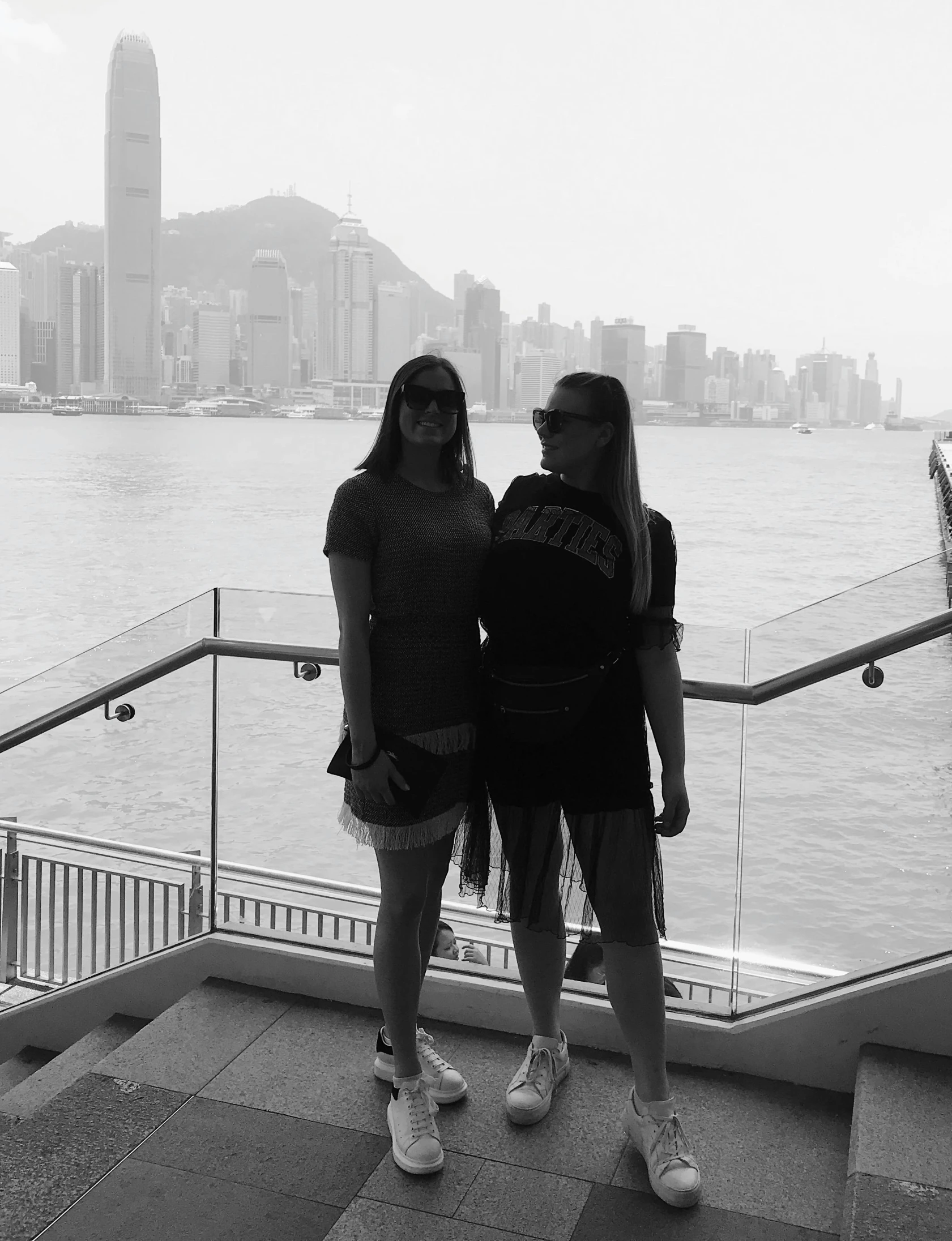 a couple of women standing next to each other, a black and white photo, inspired by Wang Duo, happening, harbour in background, snapchat photo, full body shot!!, lv