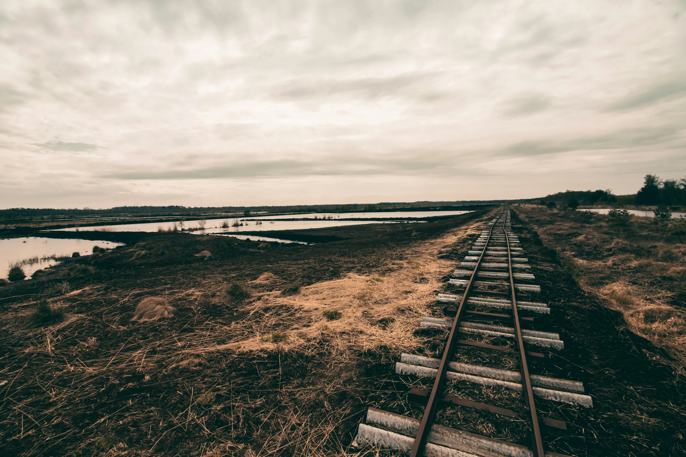 a long train track running through the desert near water