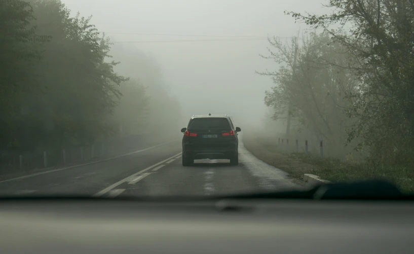 a car driving down the road on a foggy day, under a gray foggy sky, documentary photo, trending photo