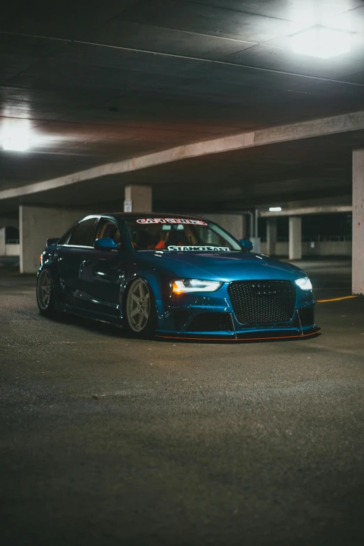 blue car parked in parking garage with a sign on it