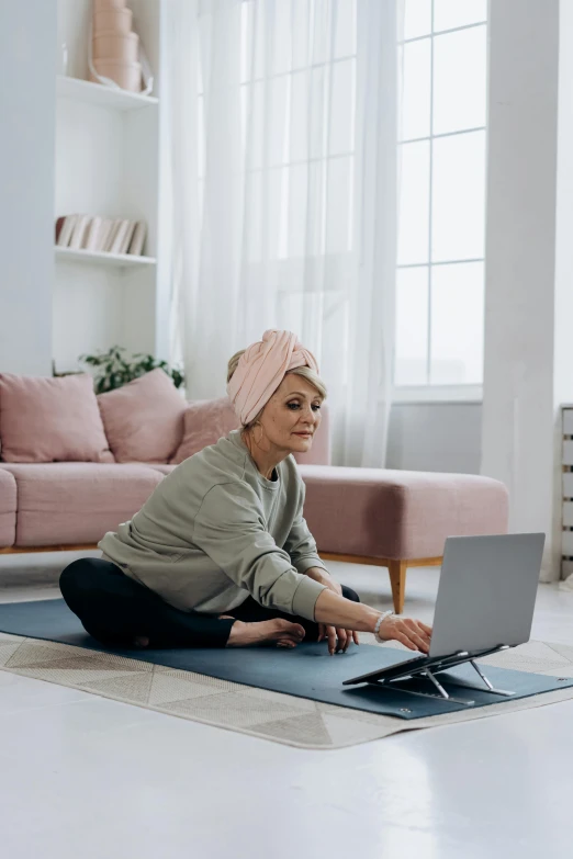 a woman sitting on a yoga mat using a laptop, tv still, turban, pixel stretching, older woman