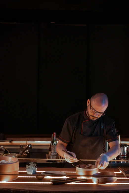 a man standing in a kitchen preparing food, a portrait, unsplash, process art, nightlife, carving, chef table, slightly minimal