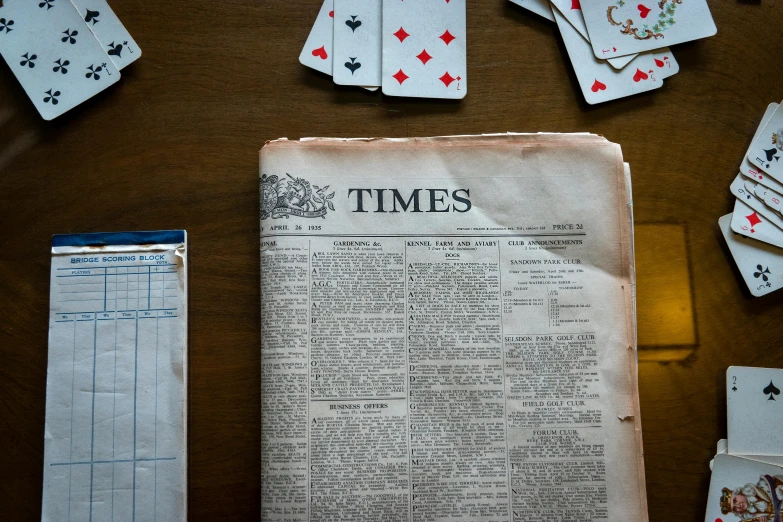 a newspaper sitting on top of a wooden table, playing cards, archive pieces, time travel theme, thumbnail