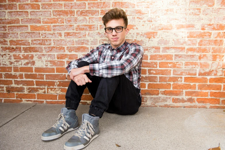 a young man sitting in front of a brick wall, inspired by Josh Bayer, antipodeans, nerdy appearance, kailee mandel, platforms, male teenager