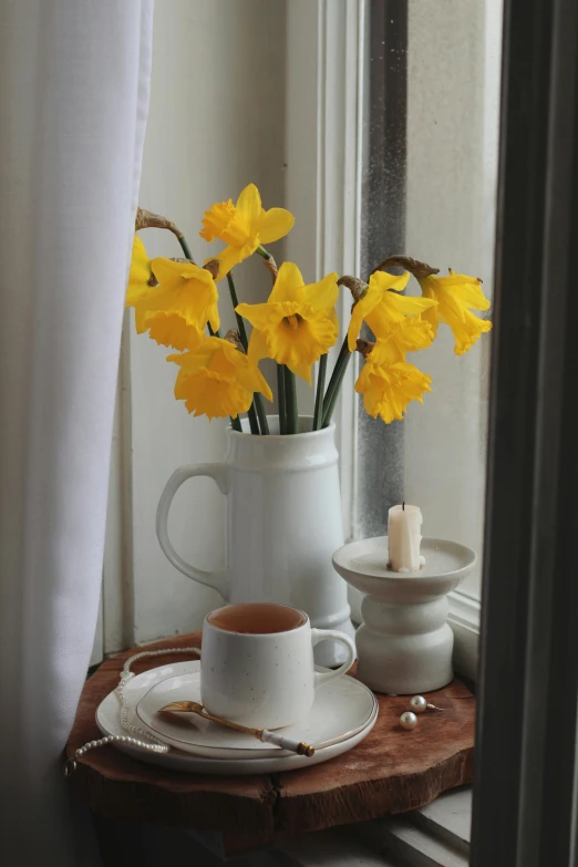 a mug, candle and flowers on a wooden tray