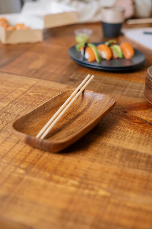 a wooden table topped with plates of sushi and chopsticks, brown ) ), square, environmental, eguchi