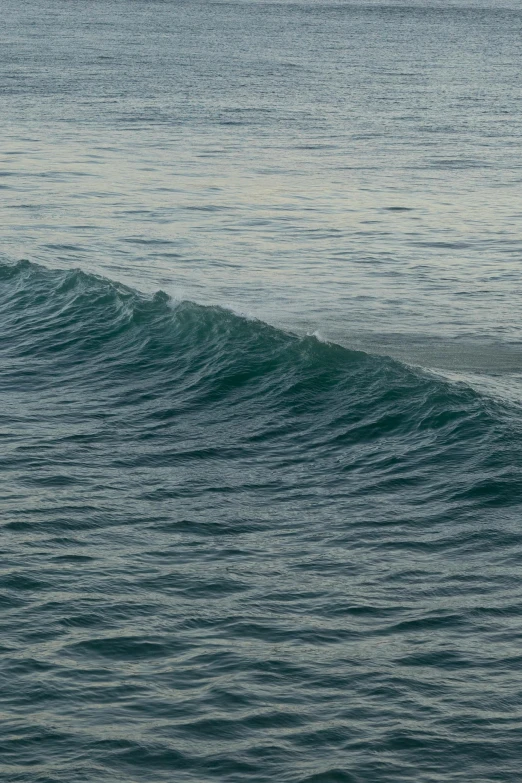 a man riding a wave on top of a surfboard, very poor quality of photography, captured on canon eos r 6, ocean pattern, early evening