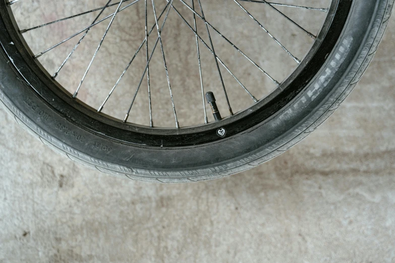 a close up of a bicycle tire on a cement floor, by Jan Rustem, hurufiyya, various sizes, wheelchair, rim - light, trimmed