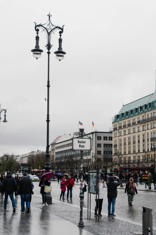 a group of people walking down a wet street, berlin secession, overcast gray skies, lots of signs and shops, on a great neoclassical square, only snow in the background