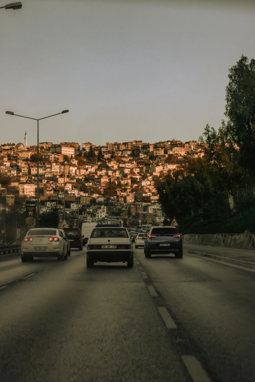 a group of cars driving down a street, by Niko Henrichon, pexels contest winner, renaissance, city on a hillside, turkey, late afternoon, poor quality