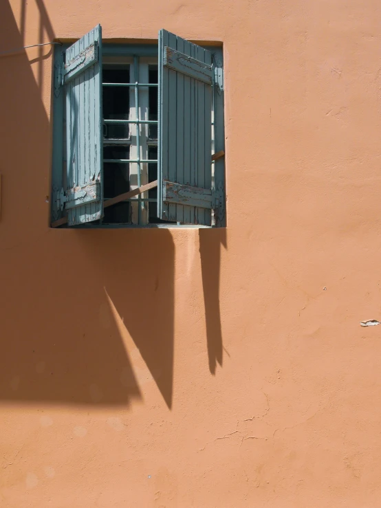 a red fire hydrant sitting on the side of a building, a picture, inspired by André Kertész, unsplash contest winner, postminimalism, marrakech, view from window, hood and shadows covering face, pale orange colors