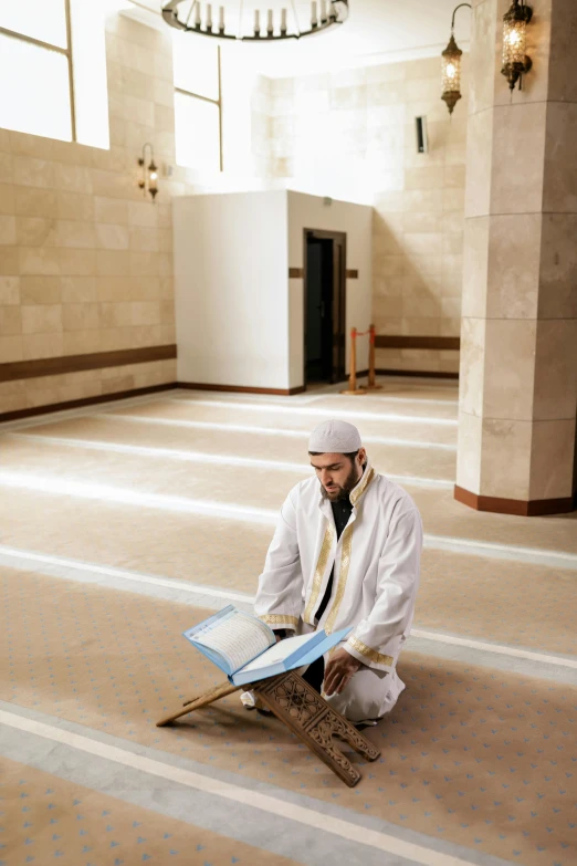 a man sits in a large room, reading the book