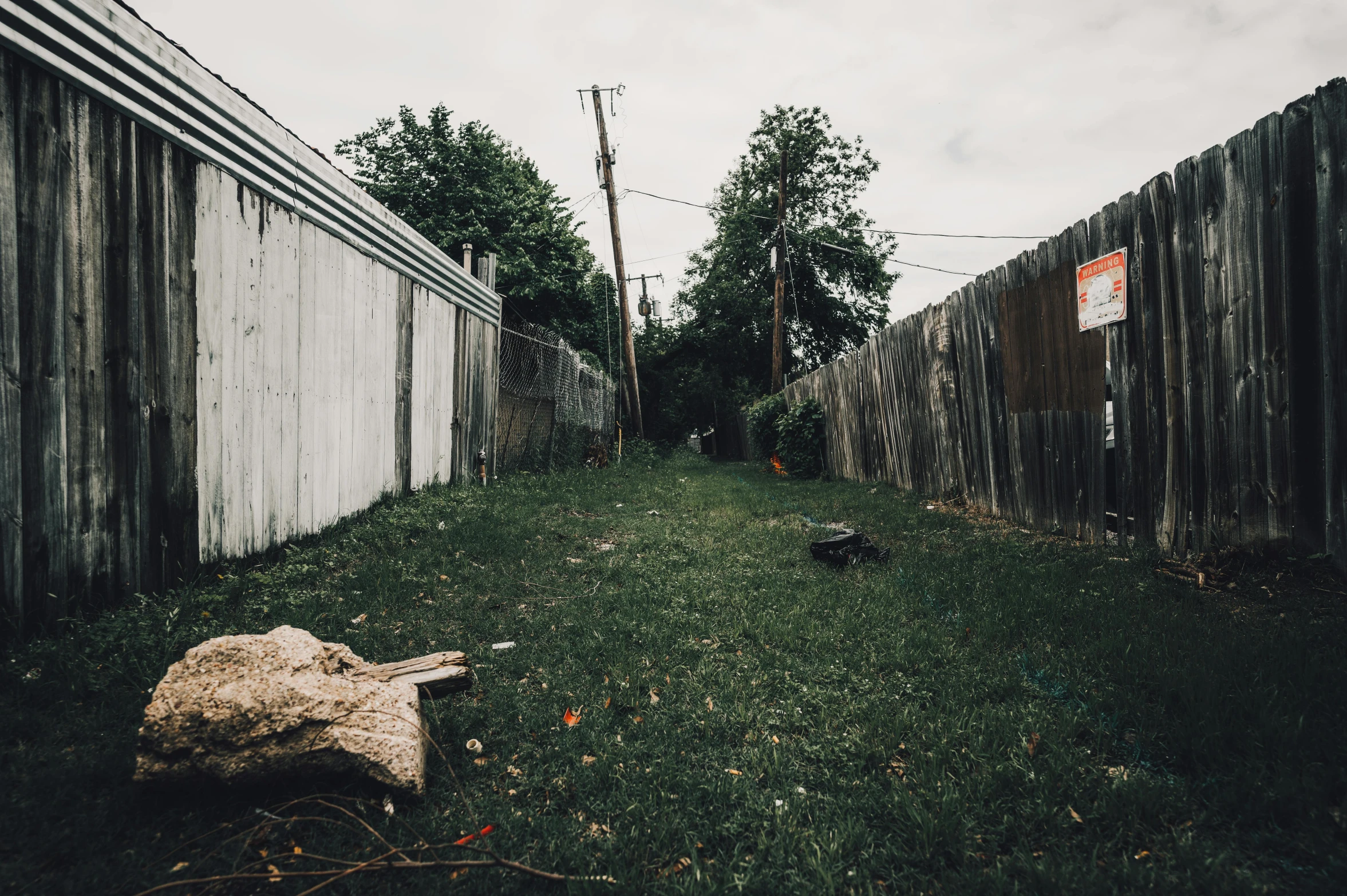 a small yard with wooden fences, and several wood trees in the distance