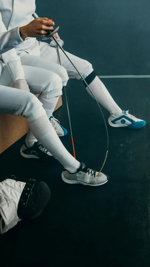 a couple of people sitting next to each other on a bench, by Adam Marczyński, trending on unsplash, renaissance, with wires and bandages, fencer, blue shoes, sports setting