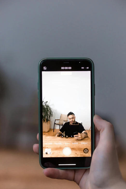 a person taking a picture with their cell phone, trending on pexels, video art, centered in portrait, sitting on a table, giving an interview, home video footage