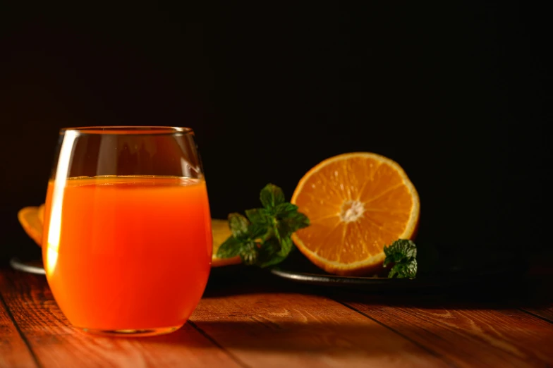 a glass of orange juice sitting on top of a wooden table, by Adam Marczyński, pexels, neon orange, background image, miniature product photo, thumbnail