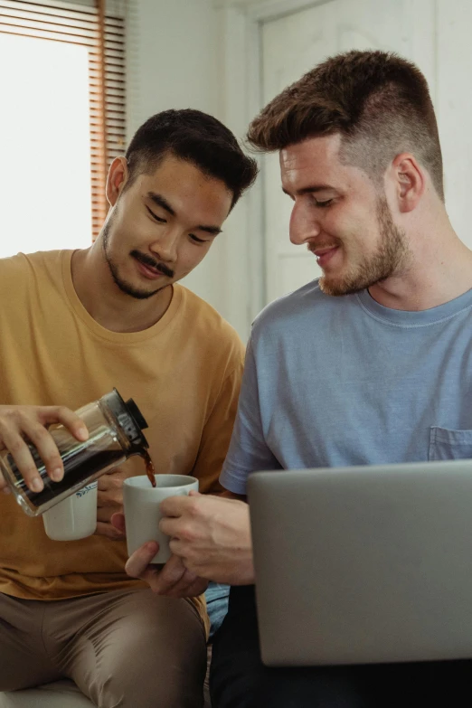 two men sitting on a couch looking at a laptop, trending on reddit, coffee machine, australian, half asian, muscular men entwined together