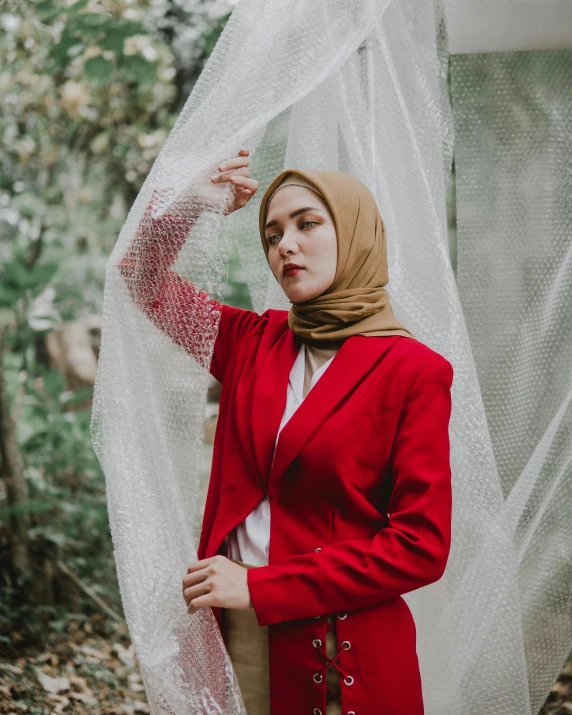 a woman standing in a forest with a veil over her head, trending on unsplash, sumatraism, wearing red formal attire, wearing a blazer, non binary model, muslim