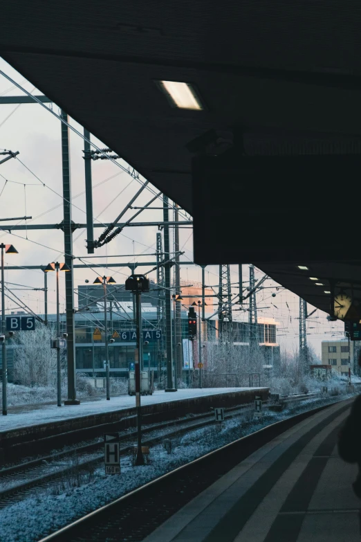 a train station with the lights on and snow on ground