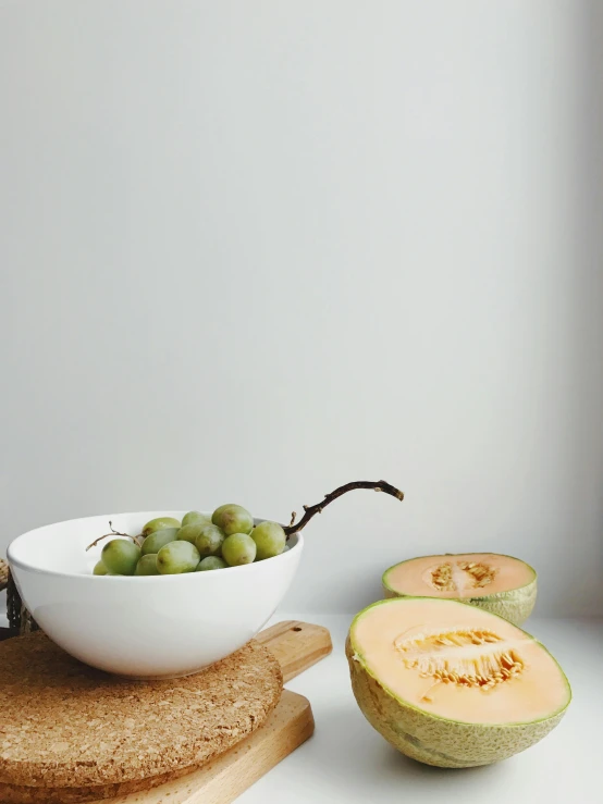 a bowl of fruit sitting on top of a cutting board, a still life, by Maggie Hamilton, unsplash, matte white background, translucent grapes, low quality photo, multiple stories